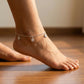 Silver anklet on a foot against a wooden floor background