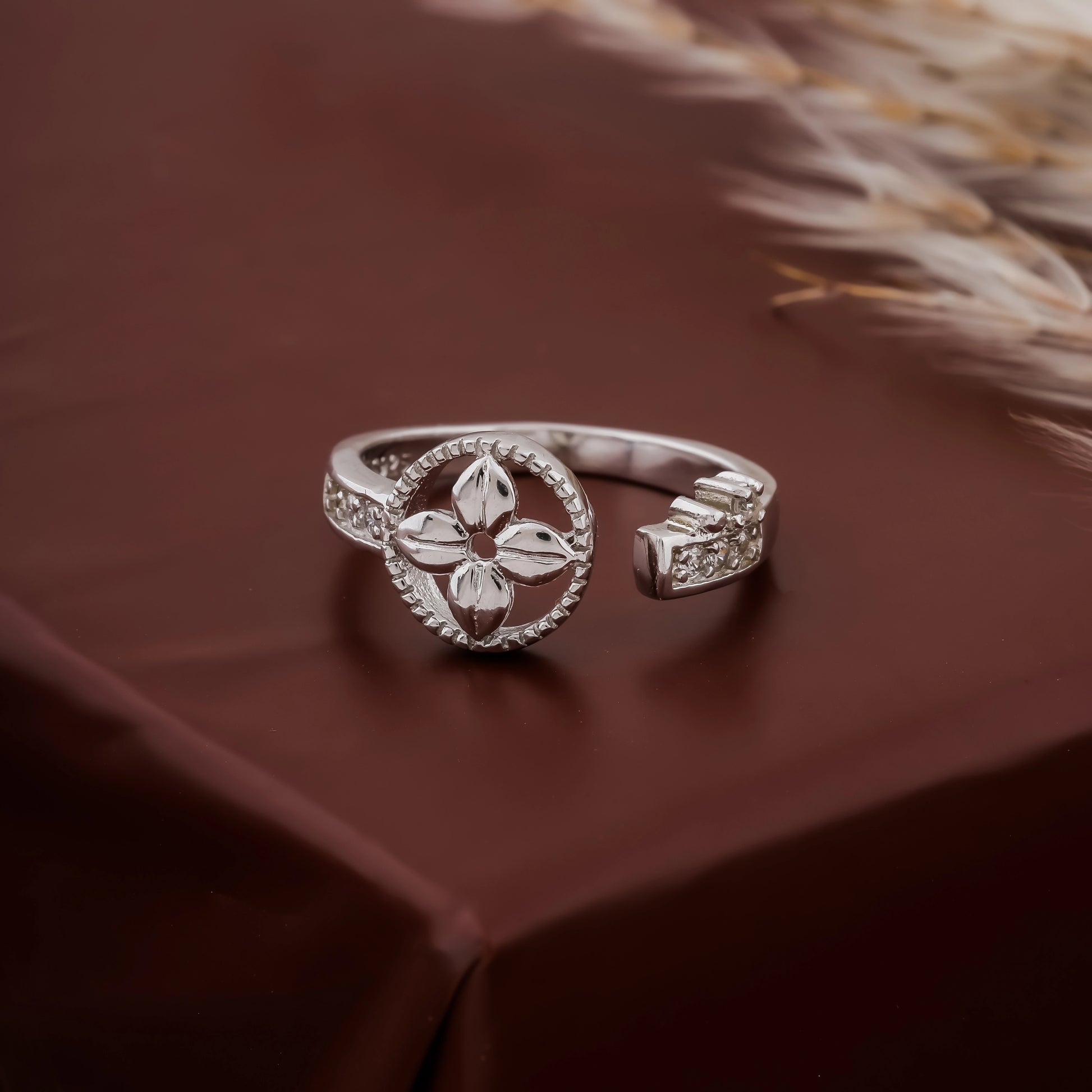 Silver ring with leaf design on a brown fabric background