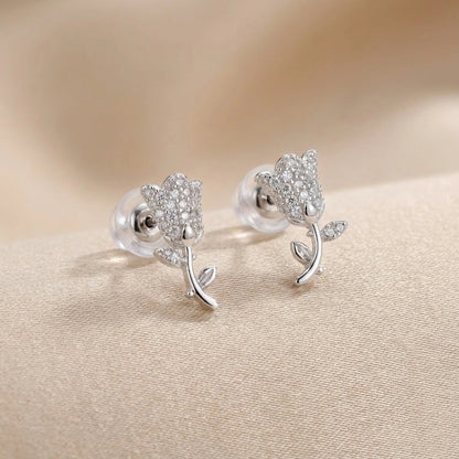 Silver flower-shaped earrings on a beige fabric background