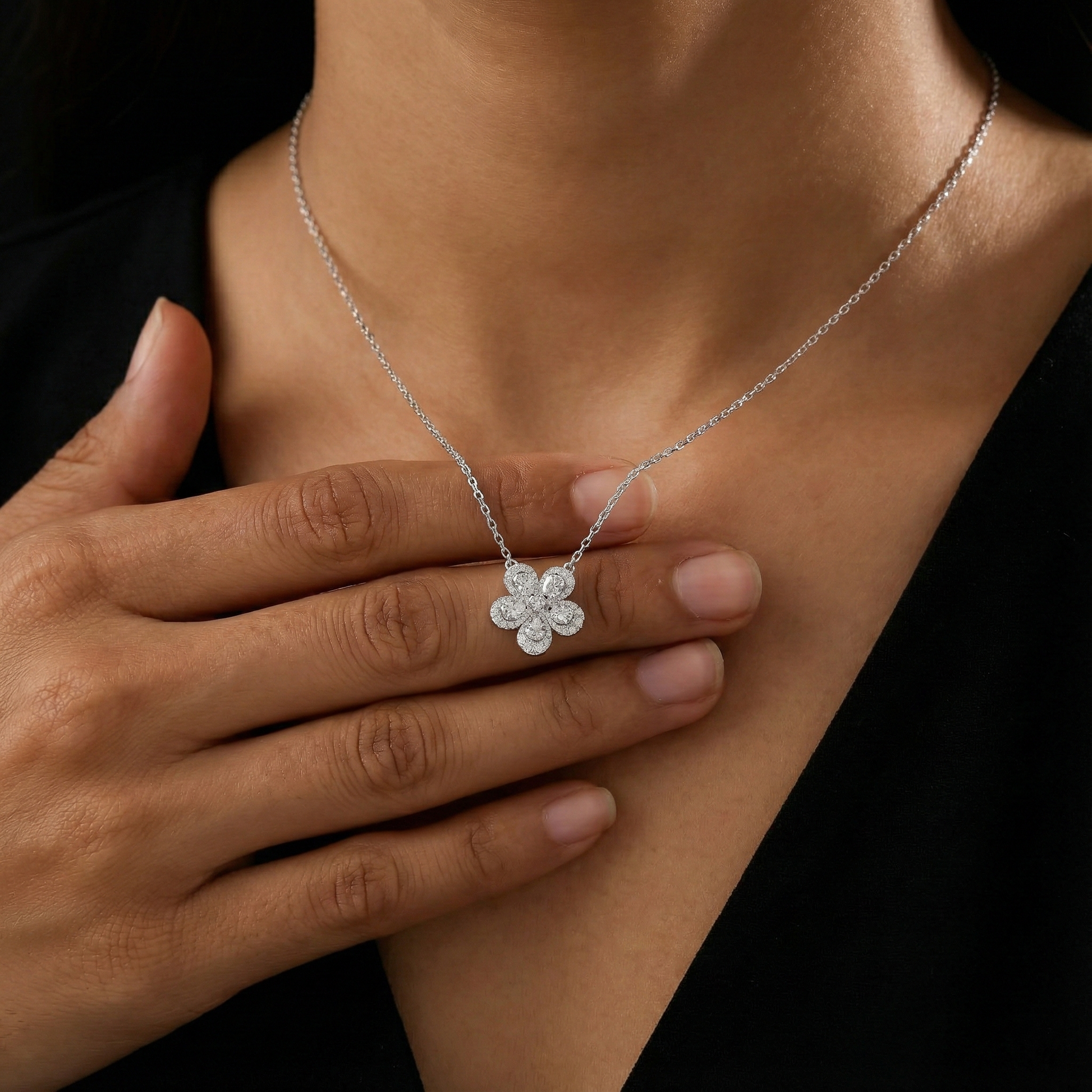 Silver necklace with a flower-shaped pendant worn by a person