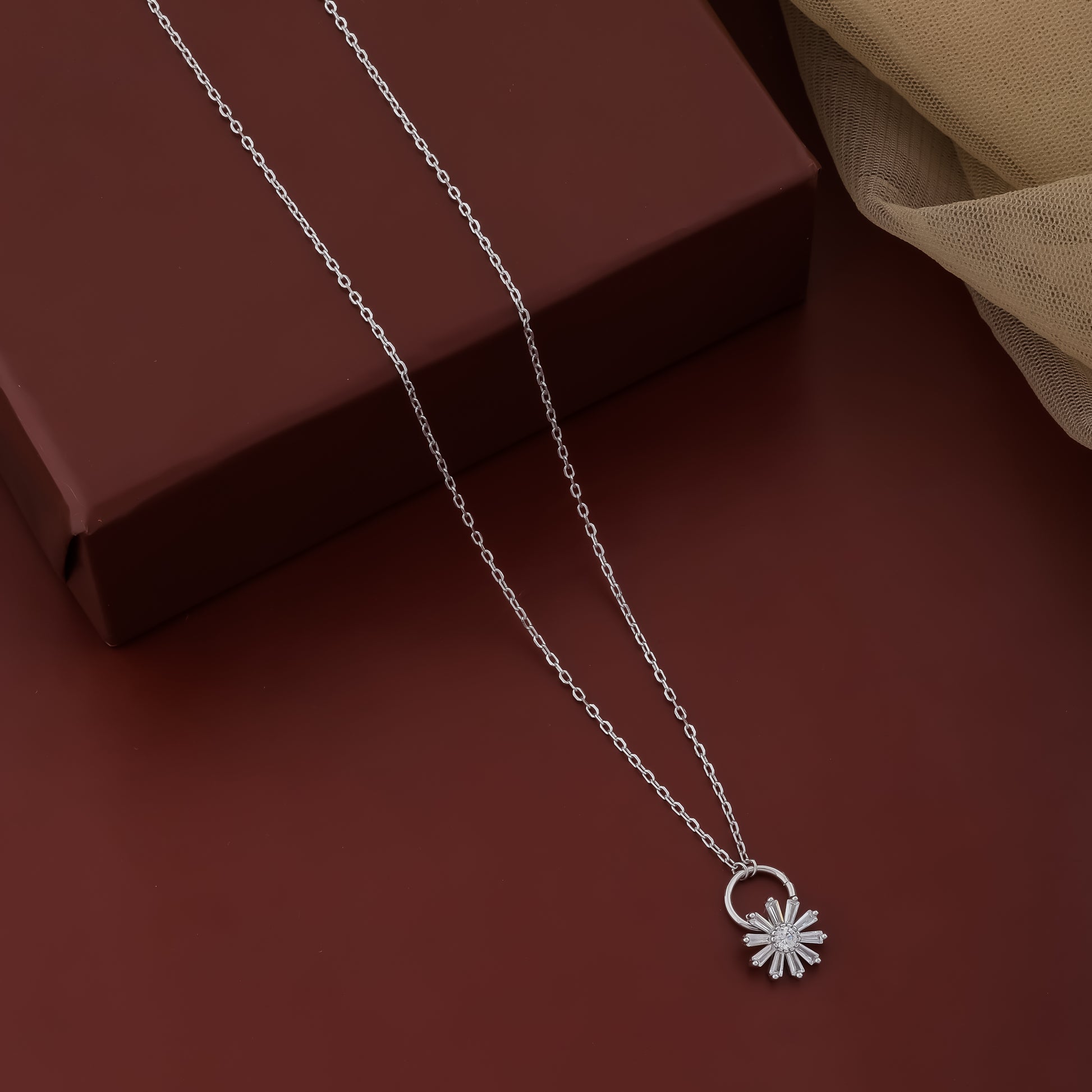 Silver necklace with a flower pendant on a brown surface