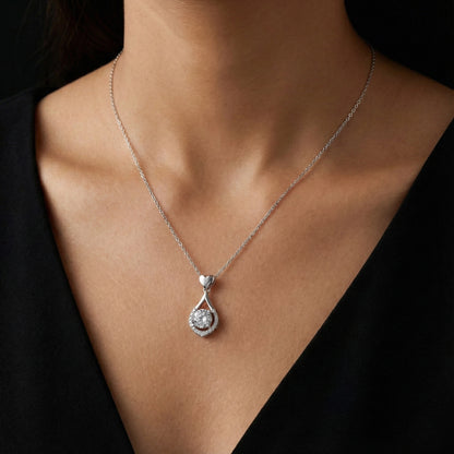 Silver necklace with a teardrop pendant on a person wearing a black top.