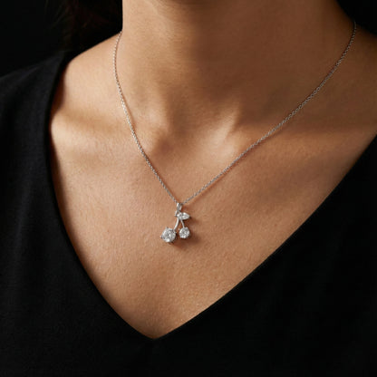 Silver necklace with a cherry pendant on a person wearing a black top.