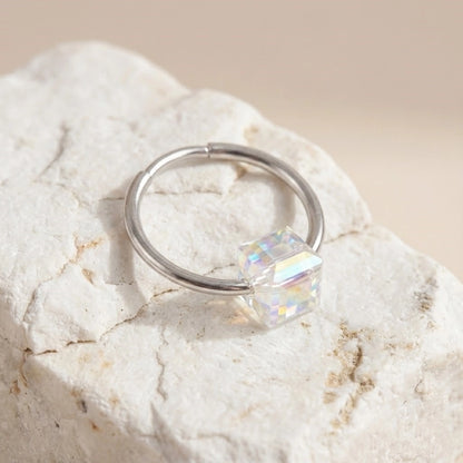 Silver ring with a square-cut gemstone on a textured stone surface