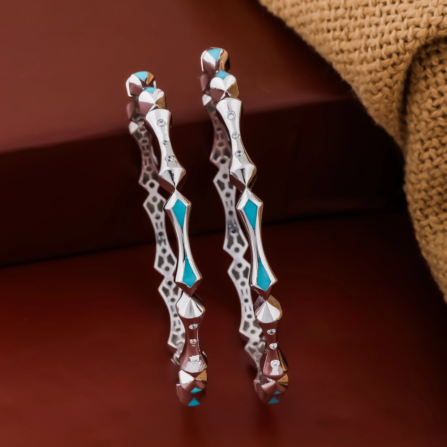 Pair of decorative earrings with blue accents on a brown background