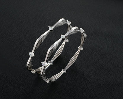 Silver bracelet with star-like embellishments on a dark textured background
