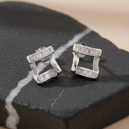 Pair of silver earrings on a dark stone surface
