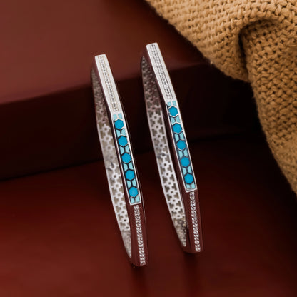 Pair of silver bangles with blue stones on a brown background