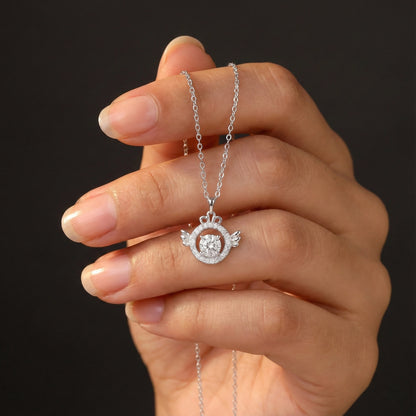 Hand holding a silver necklace with a circular pendant against a dark background