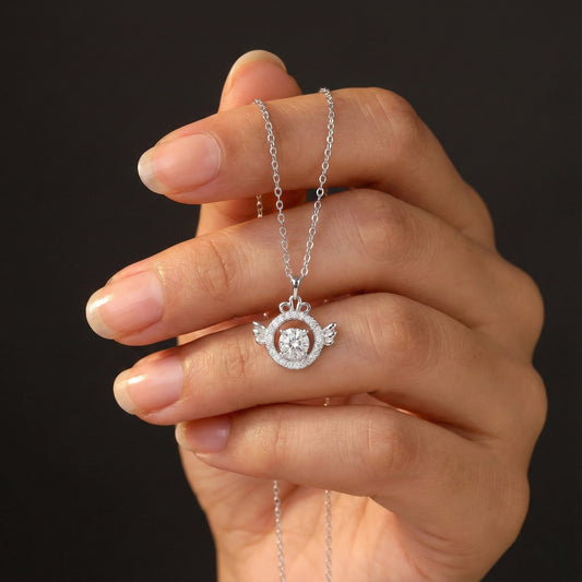 Hand holding a silver necklace with a circular pendant against a dark background