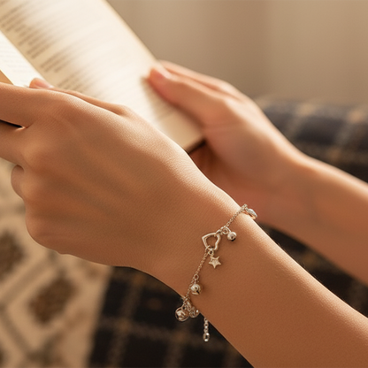 Close-up of a hand wearing a silver bracelet with charms, holding a book.