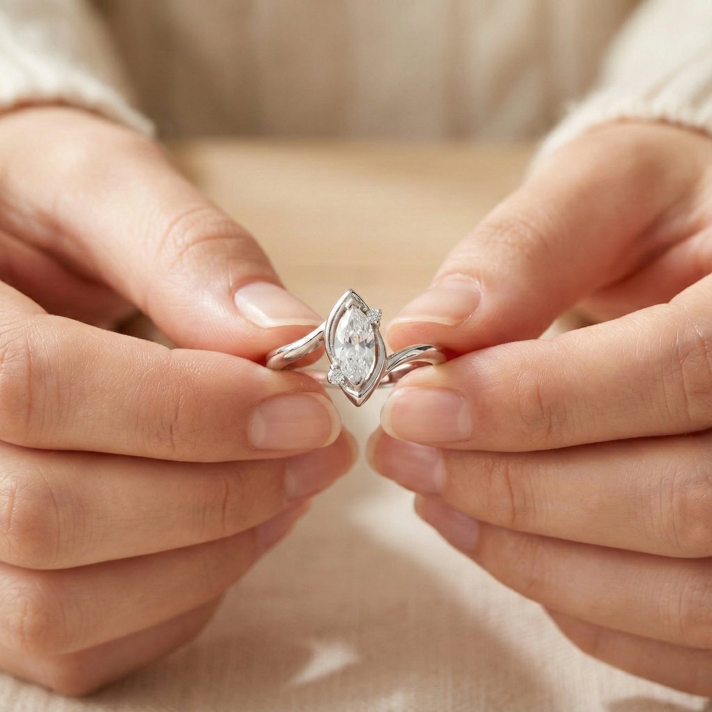 Close-up of hands holding a diamond ring against a neutral background