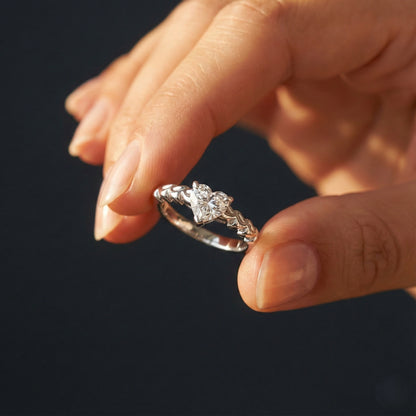 Diamond ring held between fingers against a dark background