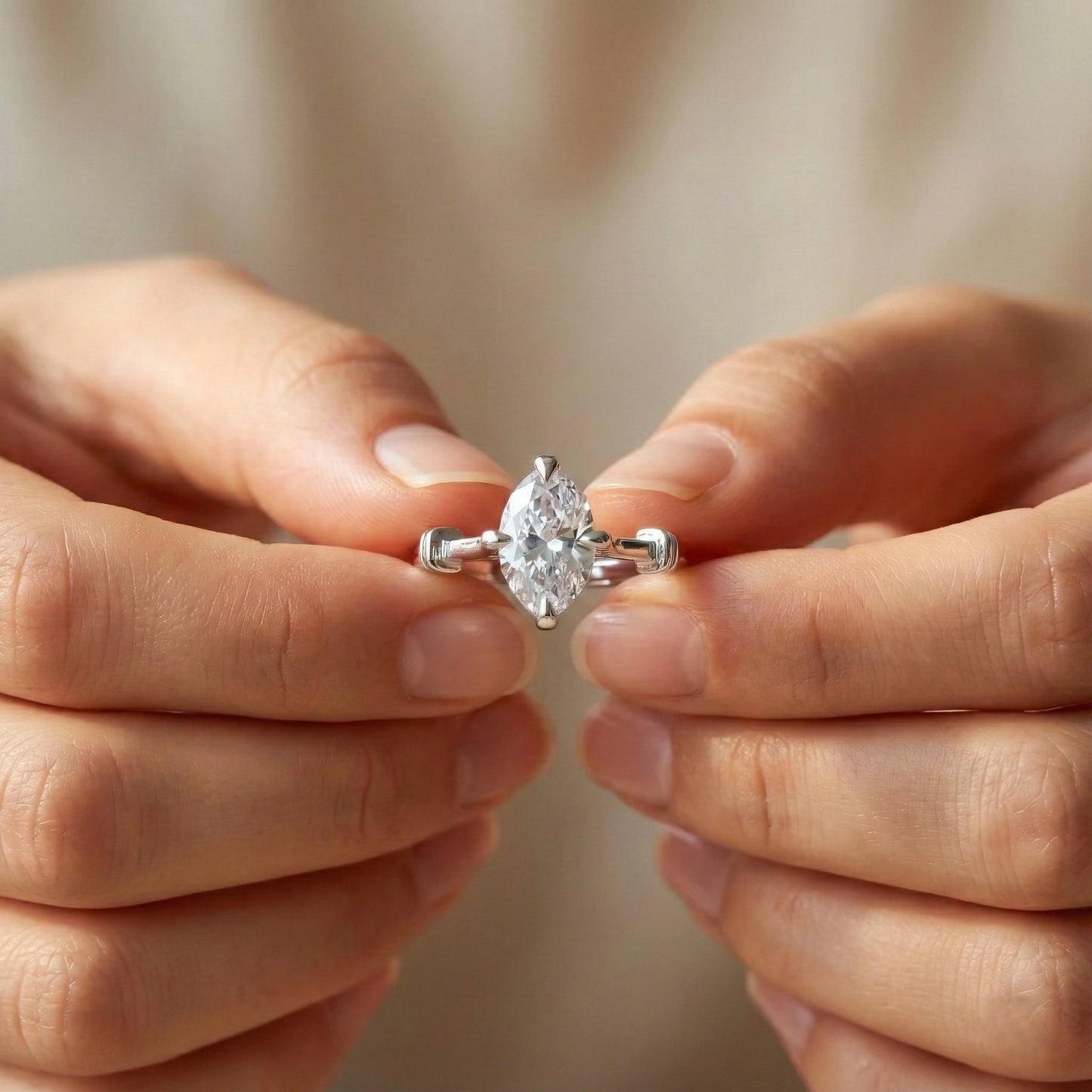 Diamond ring held between two hands against a neutral background