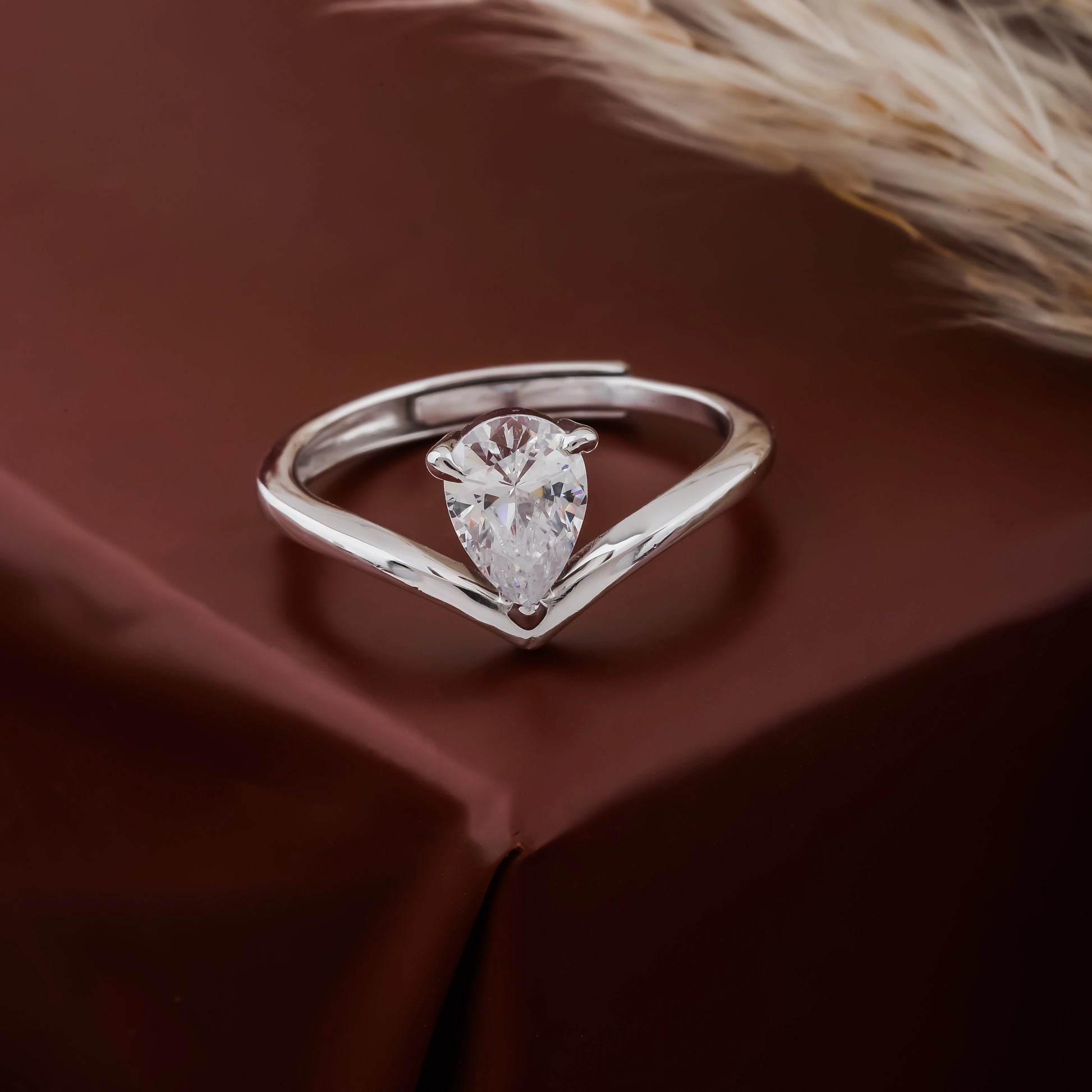 Silver ring with a pear-shaped diamond on a brown fabric background