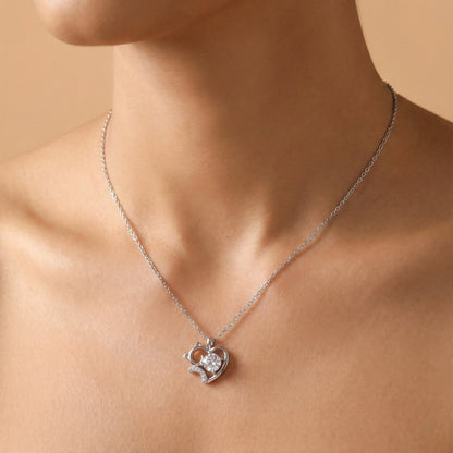Silver necklace with a heart-shaped pendant on a person against a beige background
