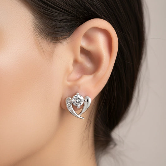Silver heart-shaped earring with a diamond on an ear against a neutral background