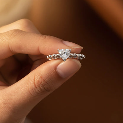 Diamond ring held between fingers against a blurred background