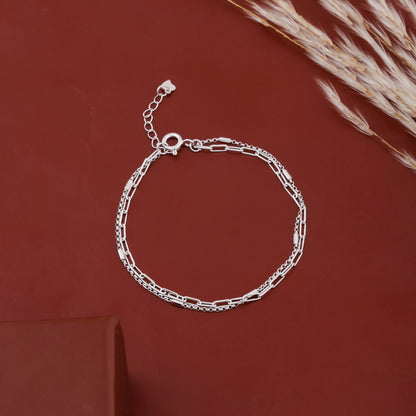 Sterling silver layered chain bracelet placed on black stone