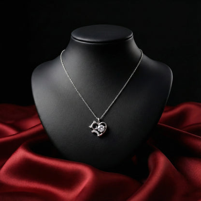 Silver necklace with a heart-shaped pendant on a black mannequin bust against a red fabric background