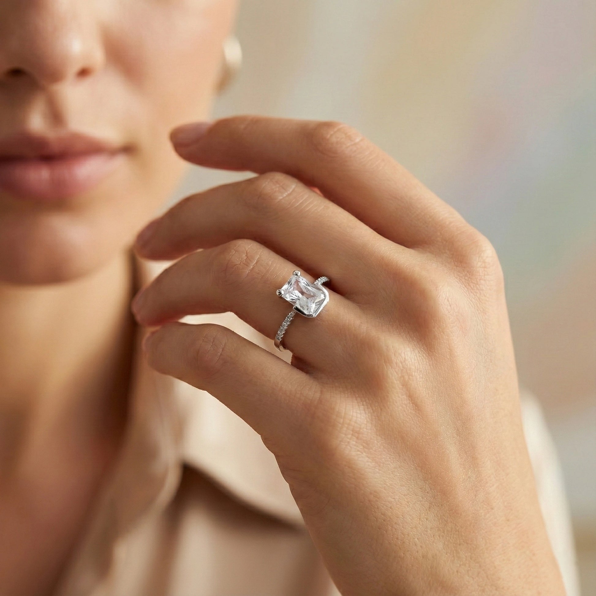 Close-up of a hand wearing a diamond ring with a blurred background
