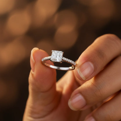 Diamond ring held between fingers with a blurred background