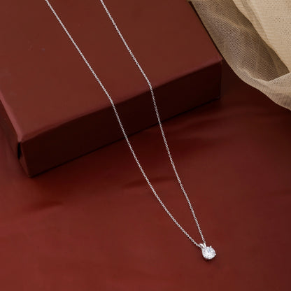 Silver necklace with a heart pendant on a red surface