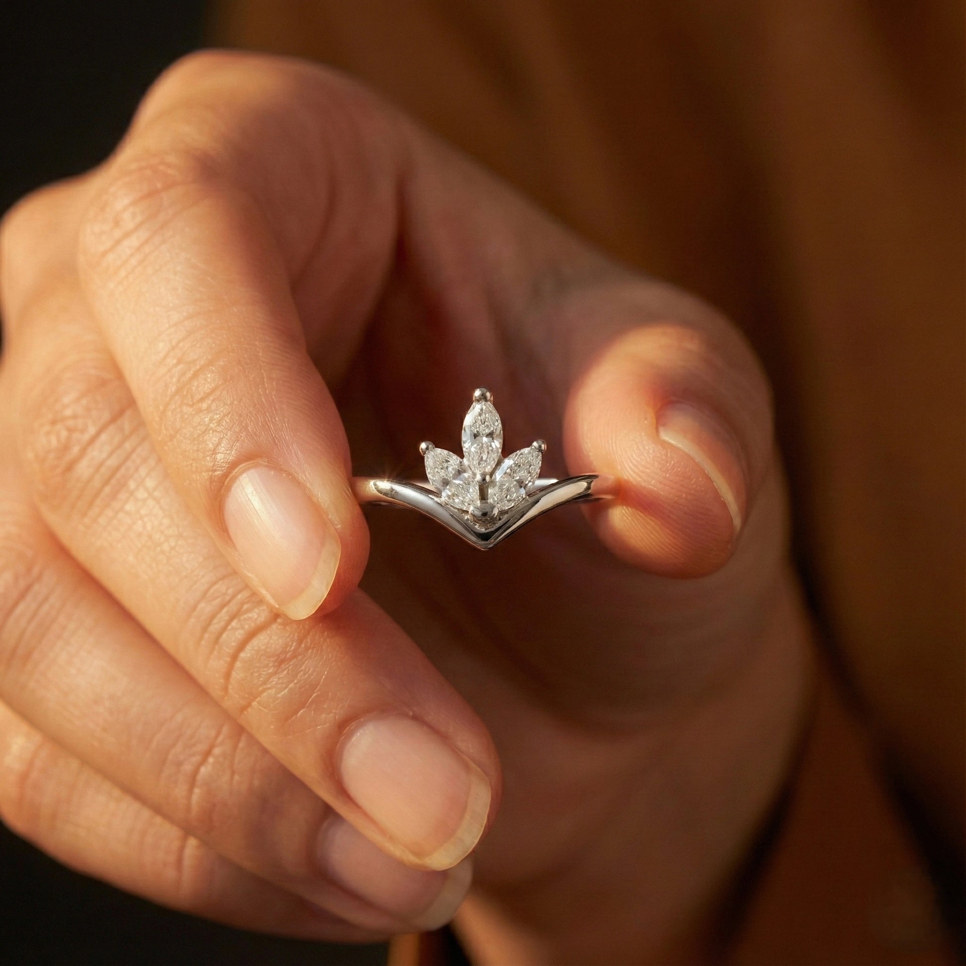 Close-up of a hand holding a diamond ring with a blurred background
