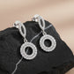 Silver hoop earrings with circular design on a dark stone surface