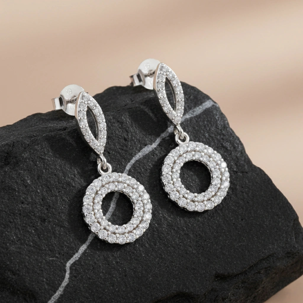 Silver hoop earrings with circular design on a dark stone surface