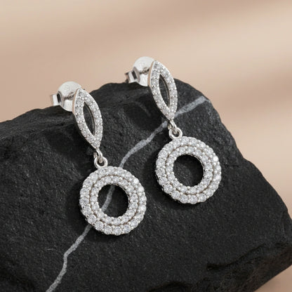 Silver hoop earrings with circular design on a dark stone surface