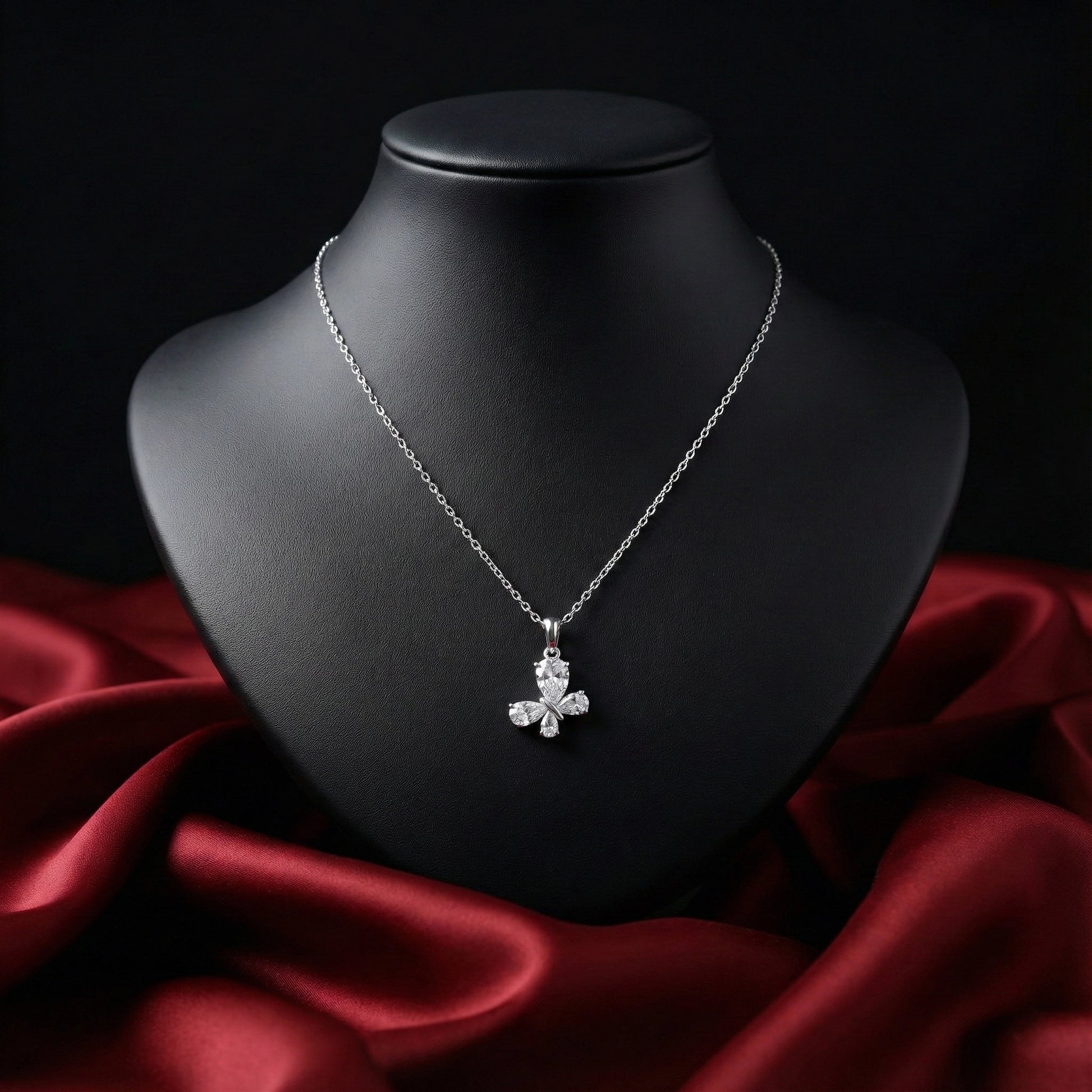 Silver necklace with a pendant on a black mannequin bust against a red fabric background