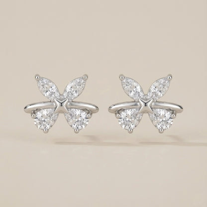 Butterfly-shaped silver earrings with clear gemstones on a beige background
