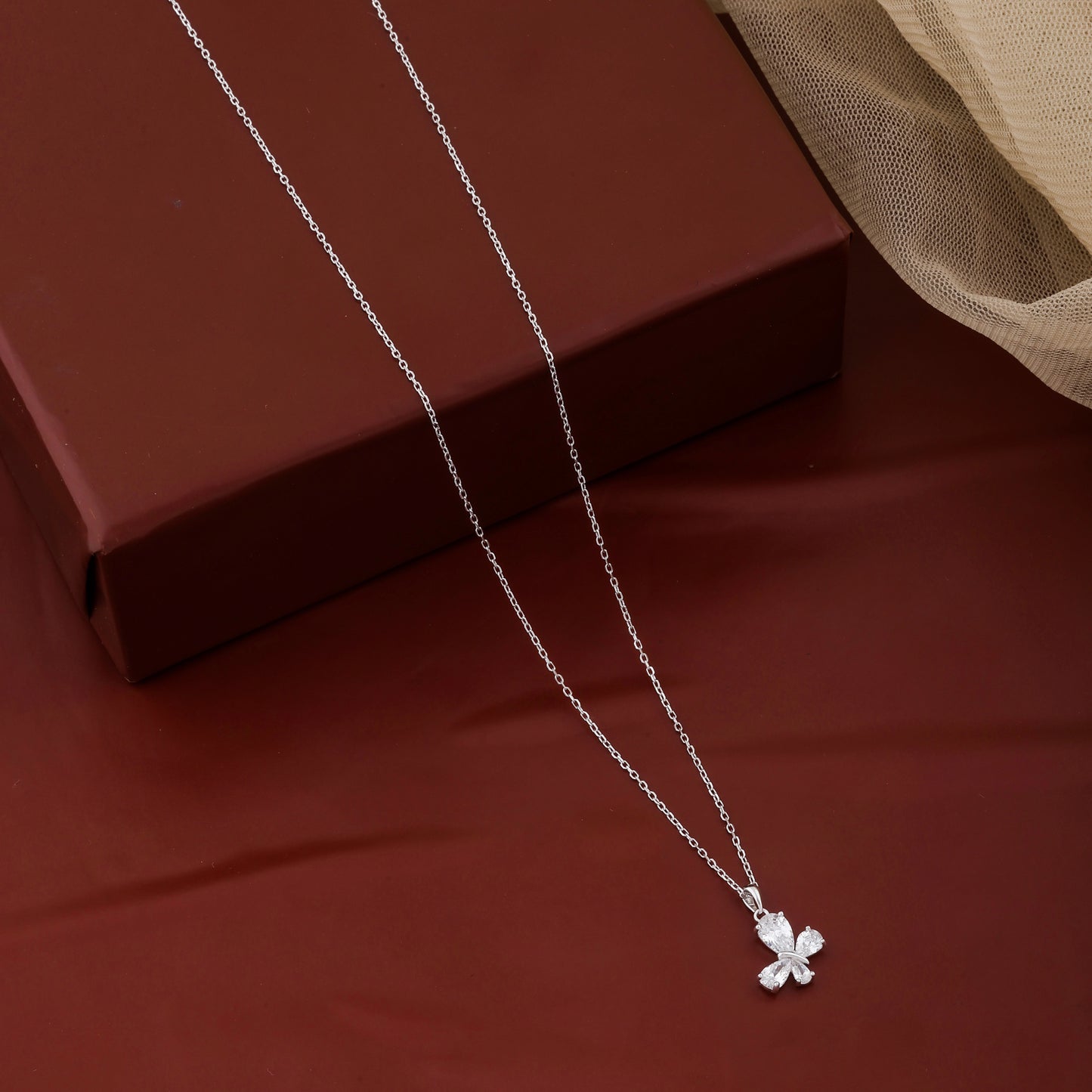 Silver necklace with a clover pendant on a red fabric background