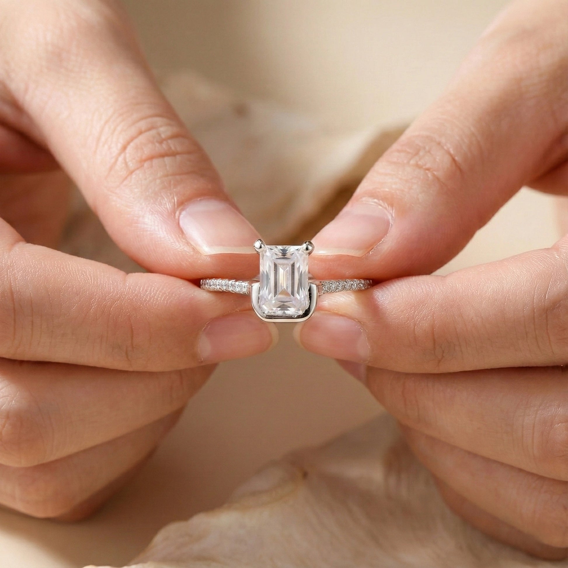 Close-up of hands holding a diamond ring with a beige background