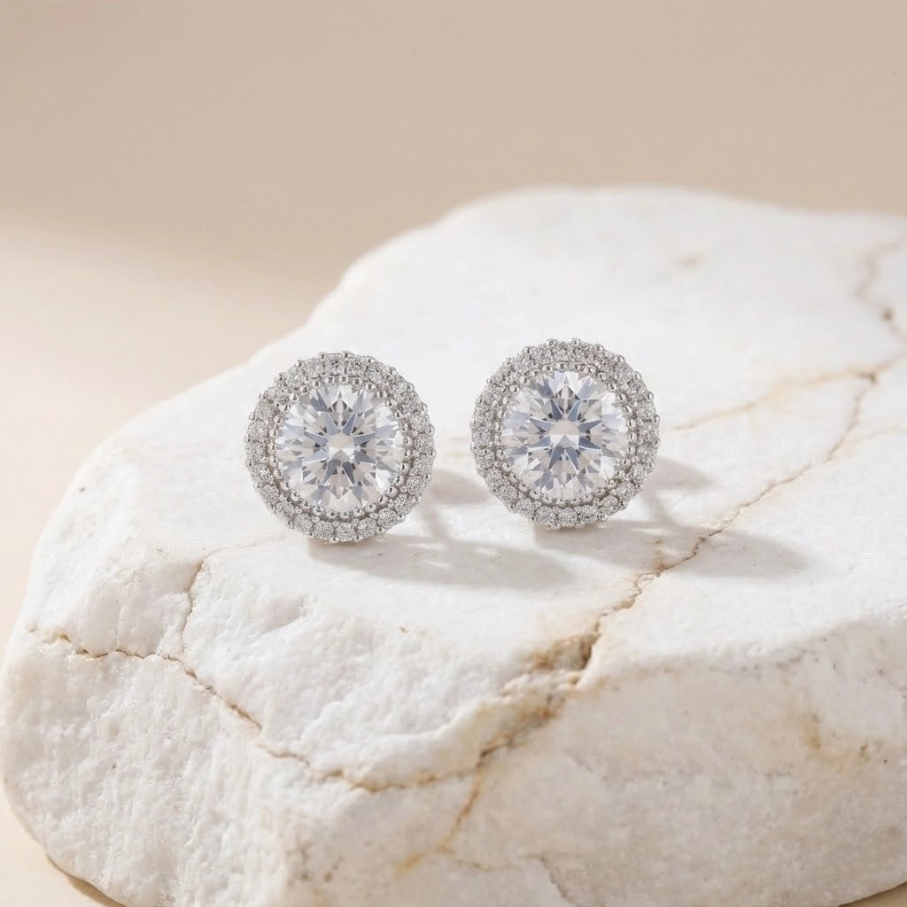 Silver earrings with clear gemstones on a textured beige surface