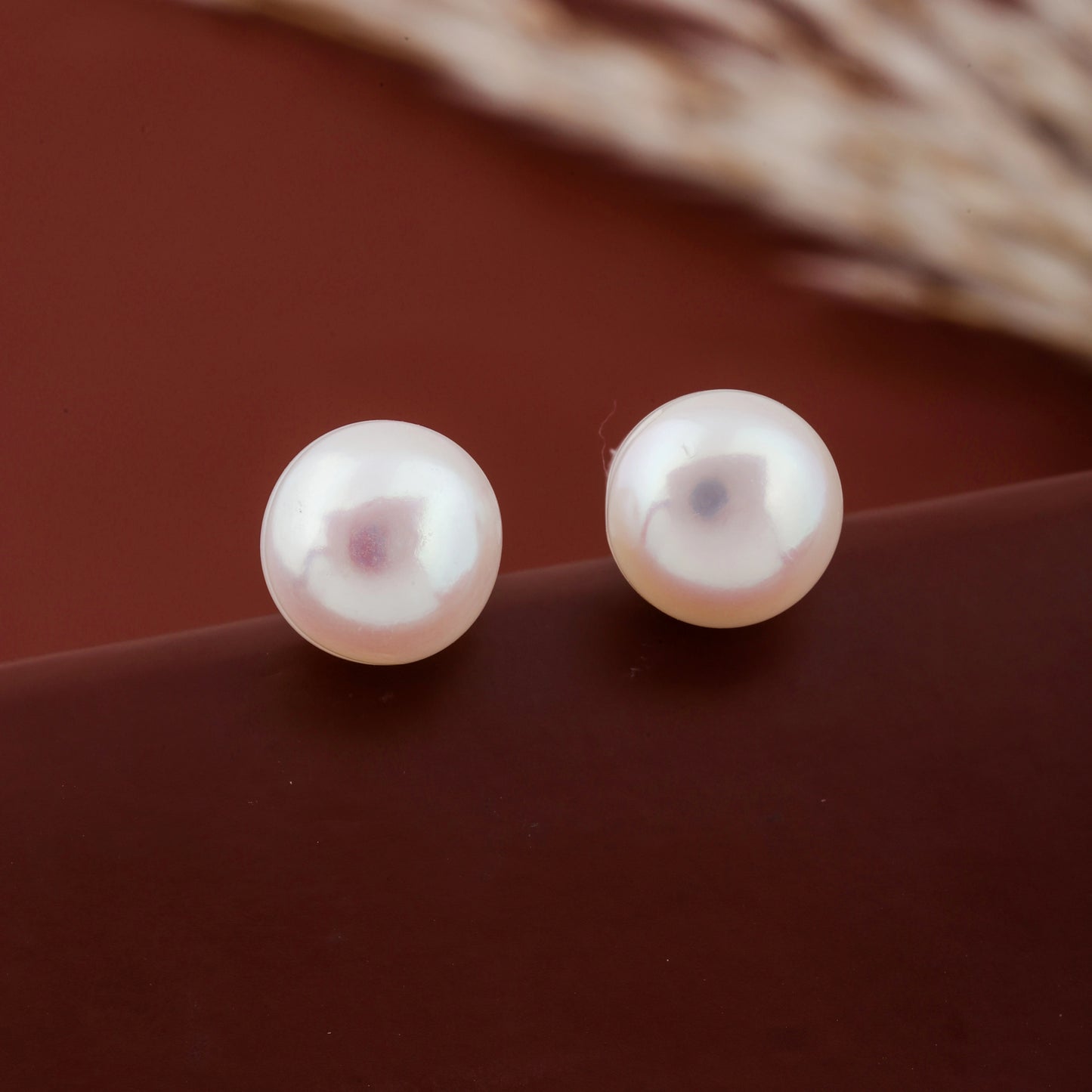 Pair of pearl earrings on a brown surface