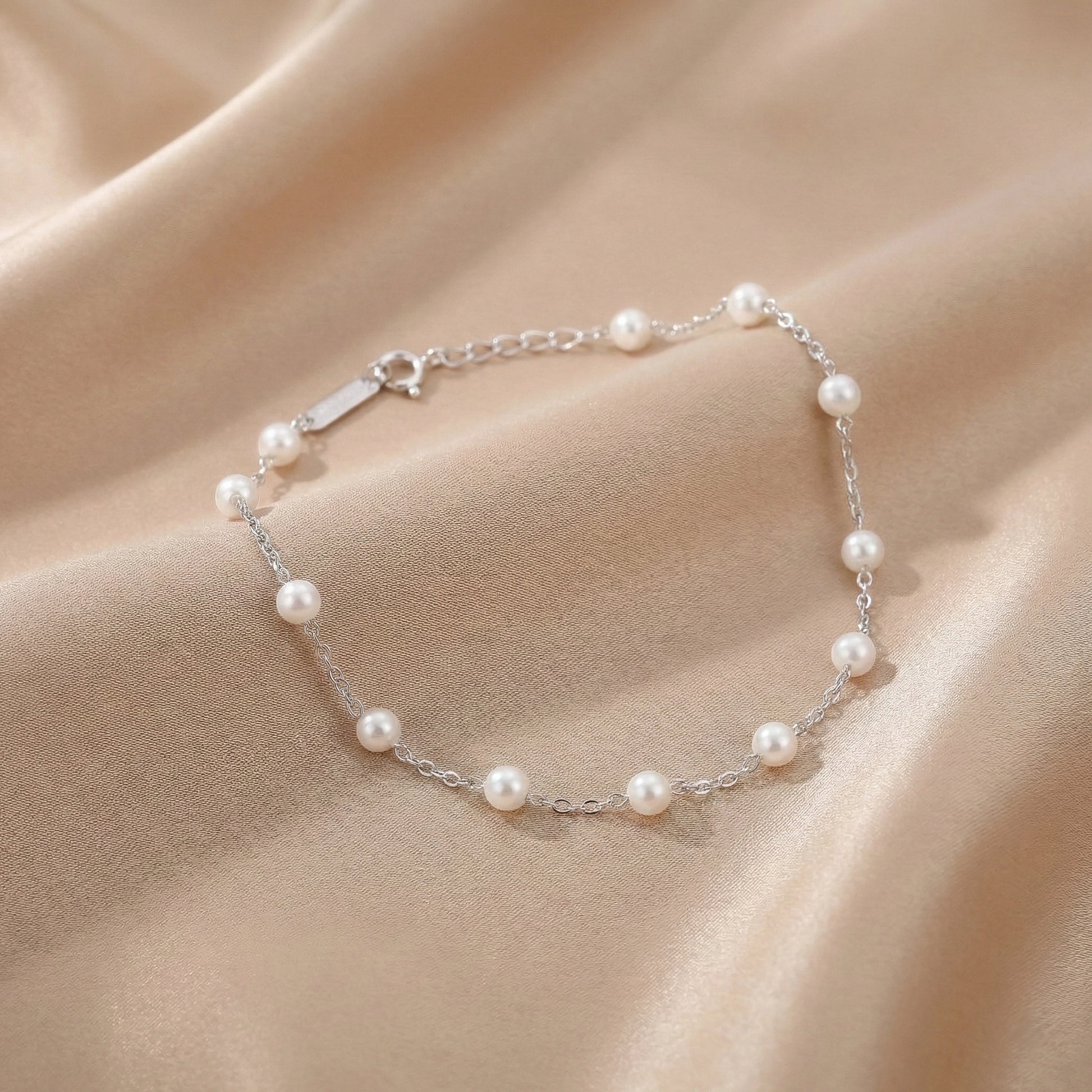 Sterling silver bracelet with white pearls placed on a black stone