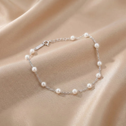 Sterling silver bracelet with white pearls placed on a black stone