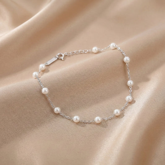 Sterling silver bracelet with white pearls placed on a black stone