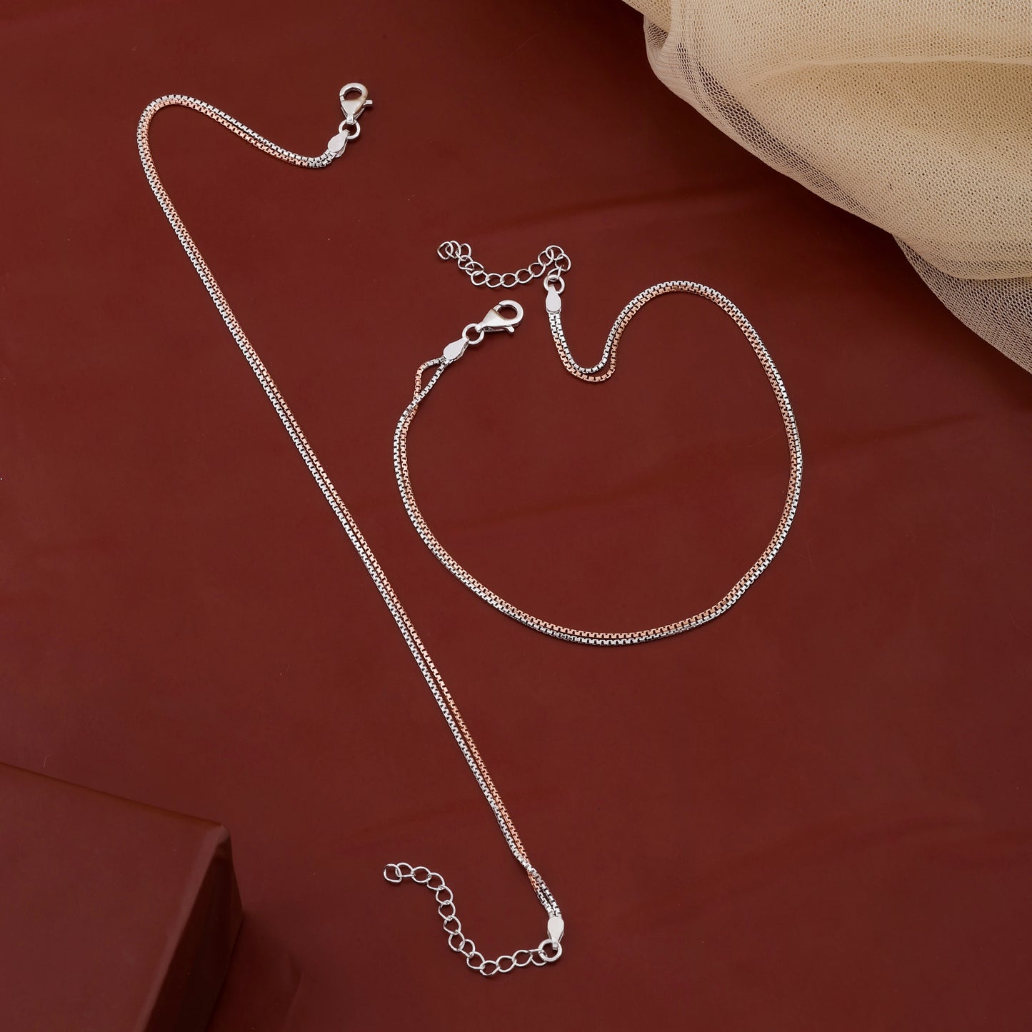 Silver necklace and bracelet set on a red fabric background