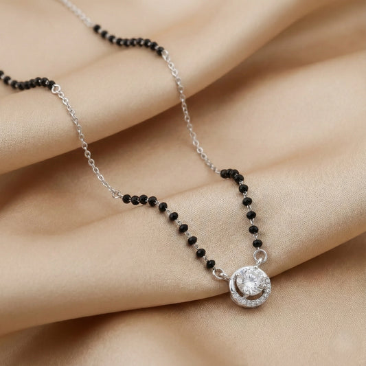 Necklace with black beads and silver clasp on a hand against a beige background