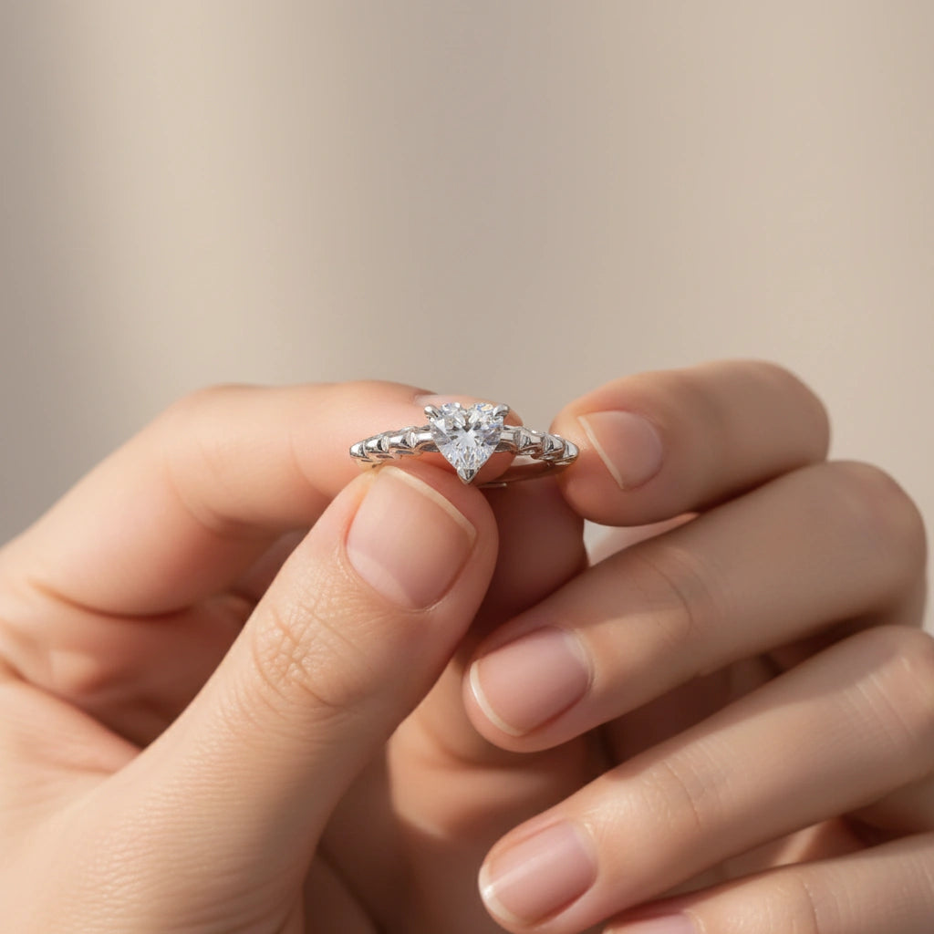 Silver diamond ring held between fingers against a neutral background