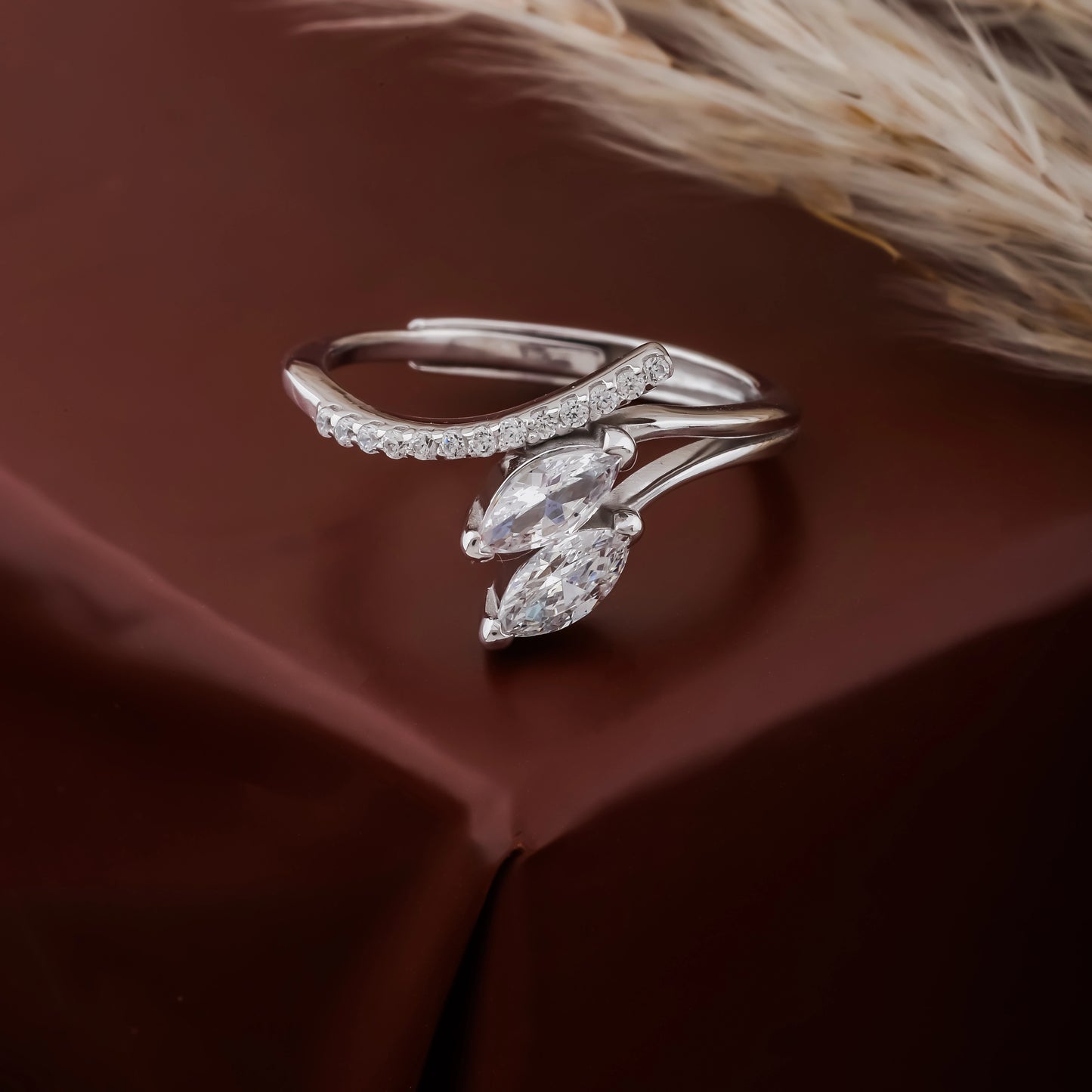 Silver ring with marquise-shaped gemstones on a brown fabric background