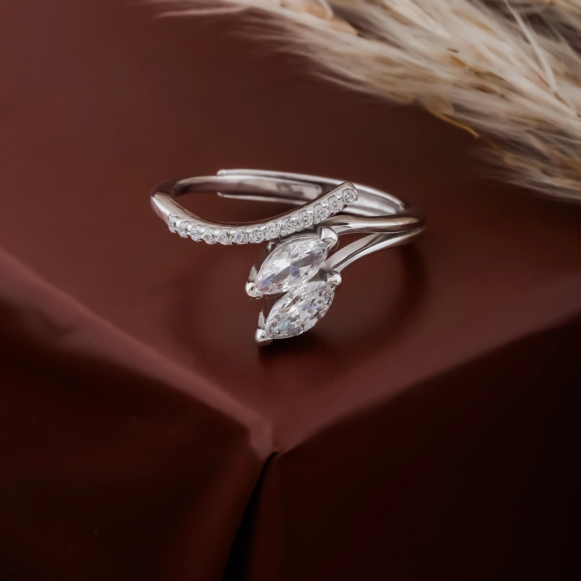 Silver ring with marquise-shaped gemstones on a brown fabric background