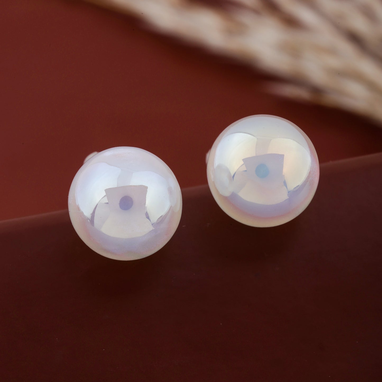 Pair of white pearl ball stud earrings showing smooth reflective finish