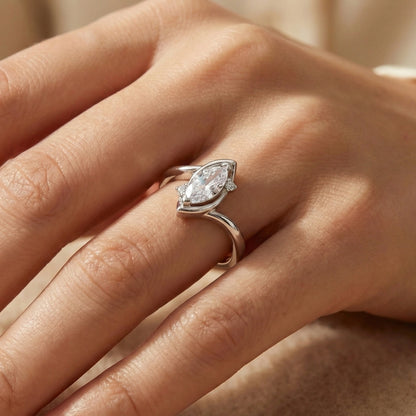 Close-up of a hand wearing a silver ring with a marquise-shaped diamond.