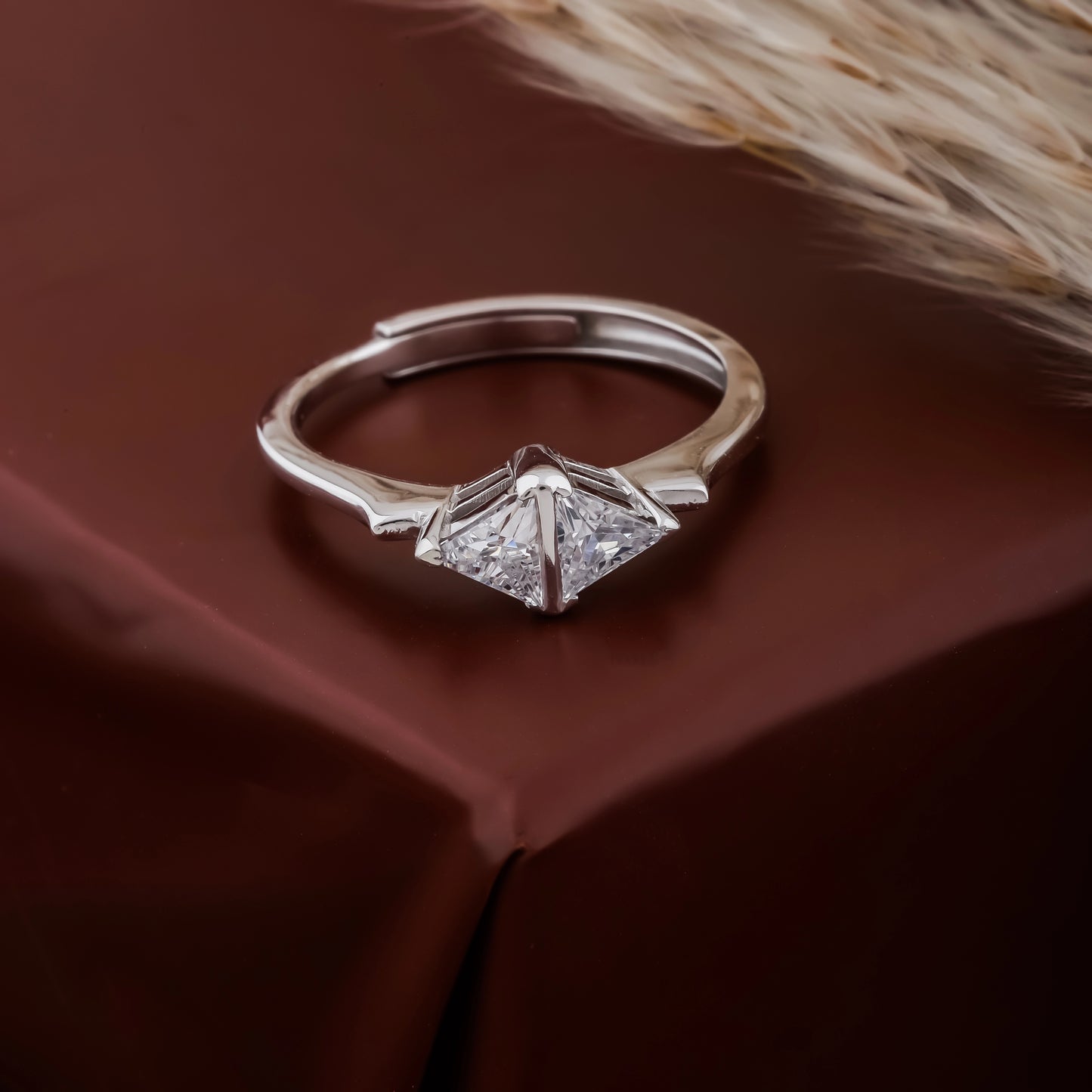 Silver ring with diamond-like stones on a brown fabric background