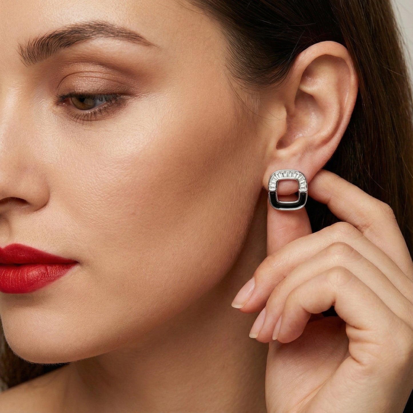 Close-up of a woman wearing a silver earring with a black square accent.