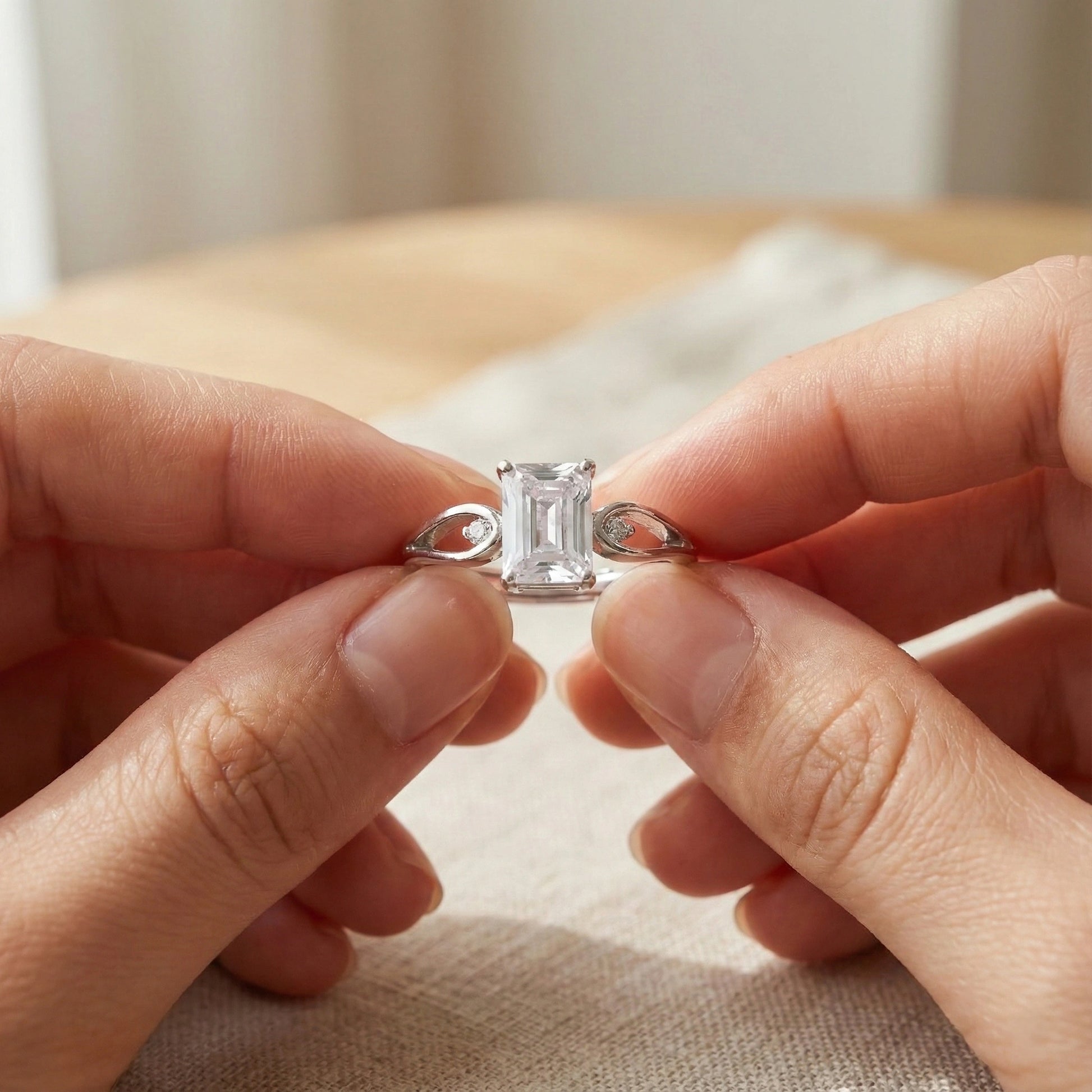 Person holding a diamond ring with a neutral background